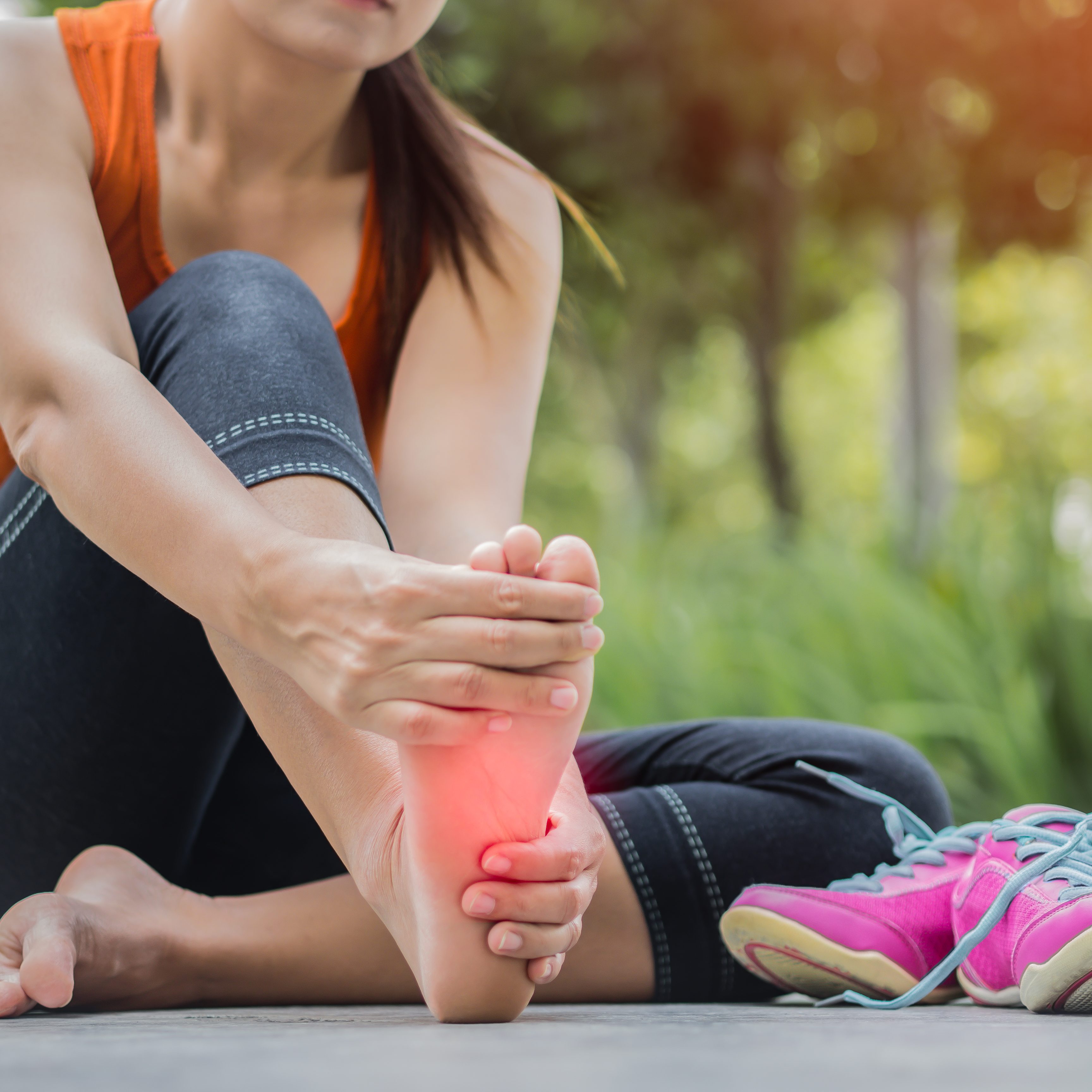 Soft focus woman massaging her painful foot while exercising.   Running sport injury concept.